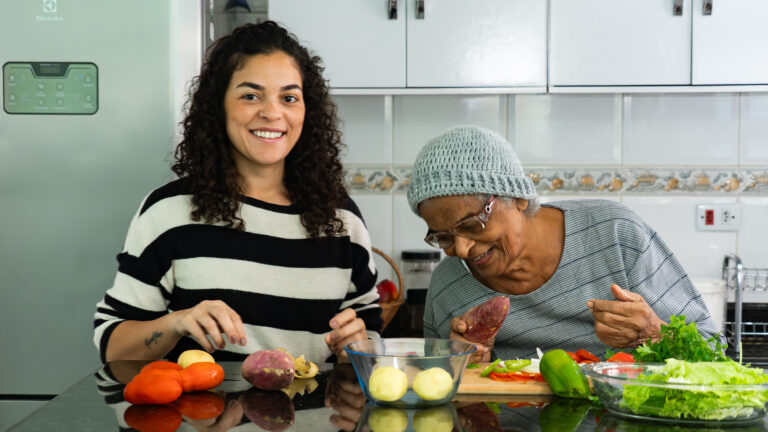 Candid Moment of Latina Woman Cooking with Elderly Afro Grandmother at Home