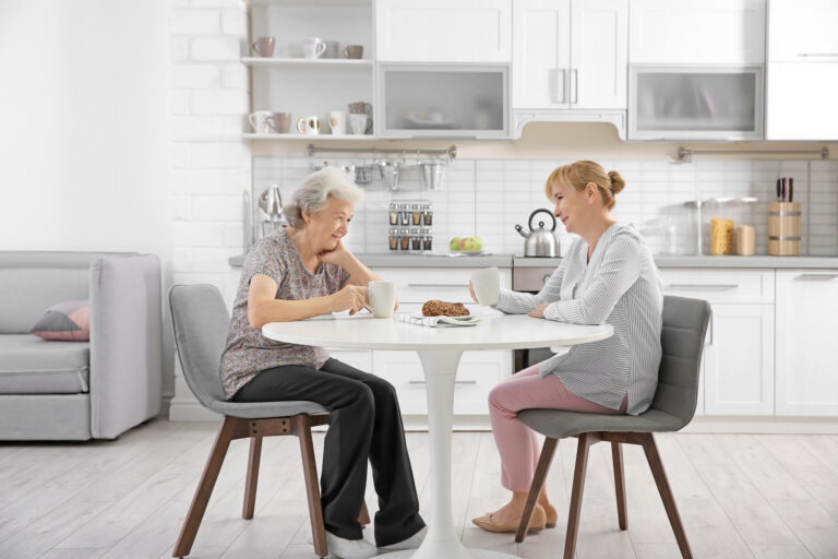 Senior woman and caregiver drinking tea at home